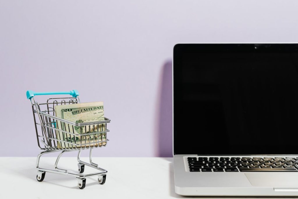pexels photo 5632397 Shopping cart with money next to a laptop symbolizing online shopping and e-commerce.