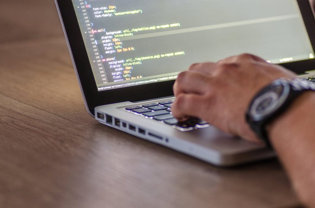 pexels photo 574071 A close-up shot of a person coding on a laptop, focusing on the hands and screen.